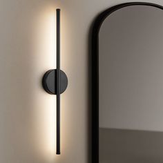 a wall light that is on the side of a wall with a mirror behind it