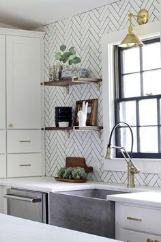 a kitchen with white cabinets and gold accents on the wall, along with an open shelving unit