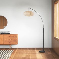 a living room with wood floors and a floor lamp next to a wooden dresser on top of a hard wood floor