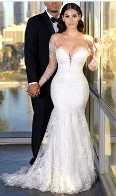 a man and woman standing next to each other in front of a glass wall holding hands