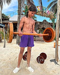 a young man is holding a barbell in the sand