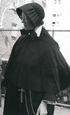 an old photo of two women dressed in black and white, one wearing a cape while the other wears a hat