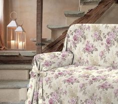 a floral couch sitting in front of a stair case next to a lamp and stairs