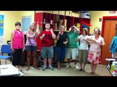 a group of people standing around each other in front of bookshelves with their hands up