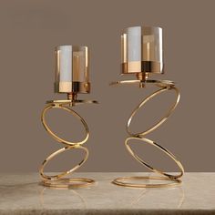 two candle holders sitting on top of a marble table next to each other with gold rings around them