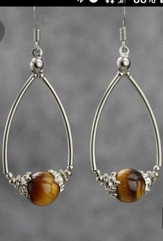 a pair of earrings with tigers eye beads hanging from it's earwires