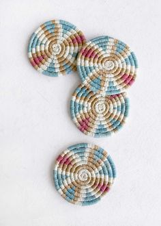 three woven coasters with different colors and designs on white table top next to each other