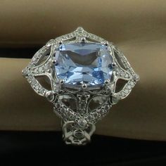 a ring with an aqua blue topazte surrounded by white gold and diamond accents