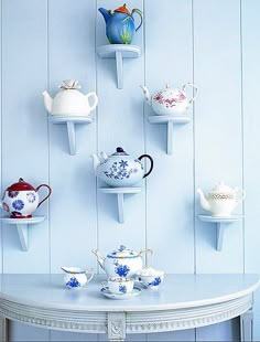 there are many teapots and cups on the wall in this room with white walls