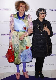 two women standing next to each other on a purple carpet