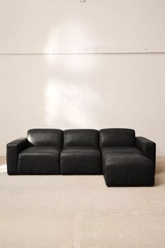 a black leather couch sitting in front of a white wall