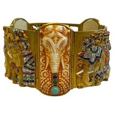 Our extraordinary 18k gold, gem-set and diamond bracelet by Fuset y Grau, circa 1930, depicts a ceremonial procession of Indian royalty including riders in howdahs on elephants, carriage drawn by oxen plus attendants and other animals including camel and tiger. Decorated with a variety of calibre-cut colored stones, including rubies, emeralds, sapphires, turquoise, coral and onyx, set on three panels separated by tinted bone carved with elephant heads and studded with cabochon stones. Measures: Spanish Art Deco, Indian Royalty, Stone Engraving, Elephant Head, Colored Stones, Gold Engraving, Leather Gifts, Indian Style, Indian Fashion