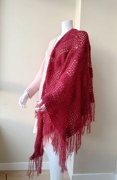 a mannequin wearing a red knitted shawl with tassels on it