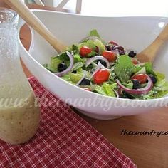 a white bowl filled with salad next to a bottle of dressing