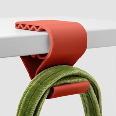 a close up of a red and green cord on a white table with an ironing board in the background