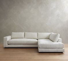 a white couch sitting on top of a hard wood floor next to a gray wall