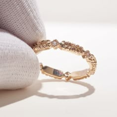 a gold ring sitting on top of a white pillow next to a pink sweater and pillows