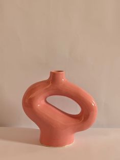 a pink vase sitting on top of a white table