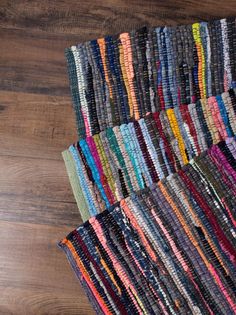 a pile of multicolored rugs sitting on top of a wooden floor