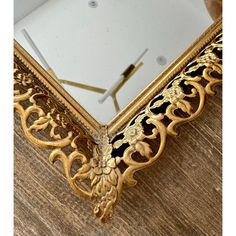 an ornate gold framed mirror sitting on top of a wooden floor next to a clock