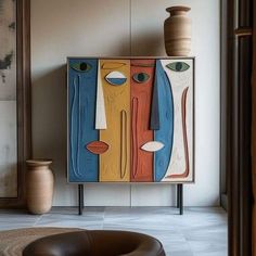 an art piece is displayed in front of a chair and vase on the wall behind it