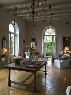 a living room filled with lots of furniture next to two large arched windows on top of a hard wood floor