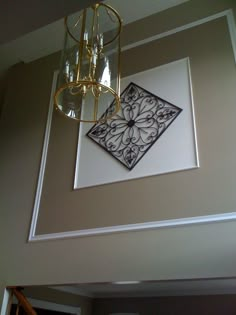 a chandelier hanging from the ceiling in a room with beige walls and white trim