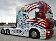 a red and white semi truck with an eagle painted on it's front side