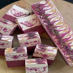 several pieces of cake with purple and gold designs on them sitting on a wooden platter