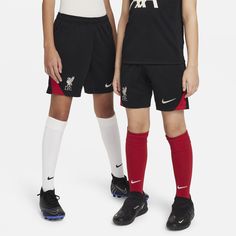 two young boys wearing black and red soccer uniforms, one is standing next to the other