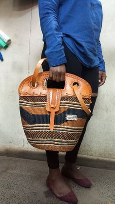 "Brown and black sisal tote bag with leather flap DIMENSIONS Bottom width: 10\" Top width: 14\" Depth: 10\" Straps: 15\" SHIPPING All orders ship via DHL Express (3-5) days delivery time." Brown Bucket Shoulder Bag With Handles, Brown Bucket Bags With Leather Handles, Eco-friendly Top Handle Bucket Bag With Leather Handles, Brown Bucket Bag With Leather Handles, Eco-friendly Bucket Bag With Leather Handles, Brown Leather Bucket Bag With Handles, Handwoven Leather Bucket Bag For Daily Use, Traditional Straw Bag With Adjustable Strap For Everyday, Eco-friendly Shoulder Bag With Leather Handles