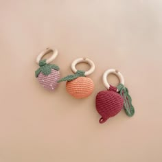 three crocheted fruit keychains on a beige background