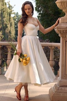 a woman in a white dress holding flowers