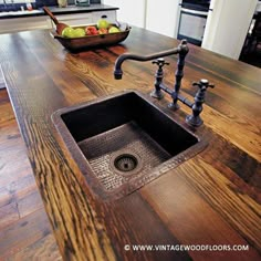 a kitchen sink sitting under a faucet on top of a wooden countertop