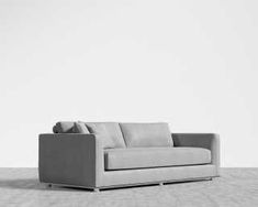 a gray couch sitting on top of a wooden floor next to a white wall in an empty room