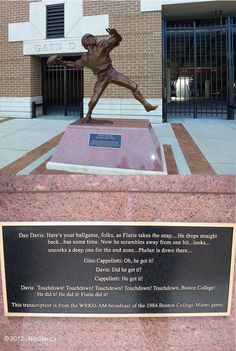 a bronze statue of a baseball player in front of a building with a plaque on it