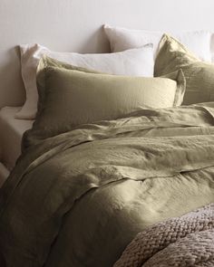 an unmade bed with green sheets and pillows