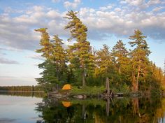 an island in the middle of a lake with trees around it and a tent on top