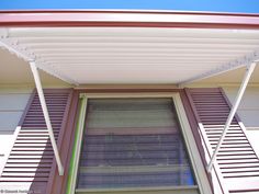 an open window with shutters and blinds on the side of a house in front of a blue sky