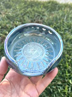 a hand holding a glass bowl in the grass