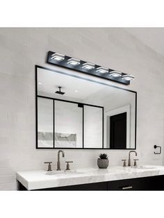 a bathroom with two sinks, mirrors and lights on the wall above them is shown