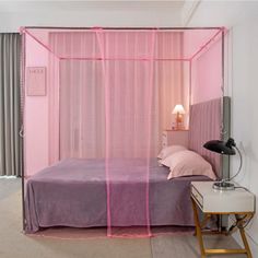 a bedroom with a pink bed and mosquito netting on the wall, along with a night stand