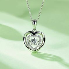 An eye-catching round moissanite dances with ease at the center of this appealing women's necklace, expressing your unstoppable love. Additional round gem set in sterling silver frame the center. Features Moissanite was originally found in meteorites(Chemical name: Silicon Carbide). It was first discovered in 1893, while a scientist was examining meteor samples from a crater in Arizona. After many years, the experts has been recreated moissanite in the laboratory, that make the gemstone with fri Elegant Diamond Necklace, Double Heart Necklace, Women's Necklace, Silicon Carbide, Moissanite Necklace, Pendant For Women, Stone Material, Moissanite Jewelry, Round Moissanite