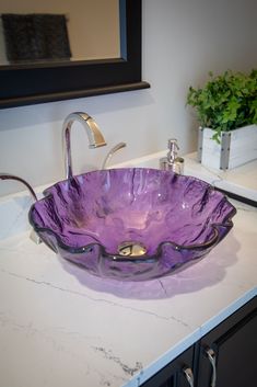 a purple glass bowl sink sitting on top of a white counter next to a mirror