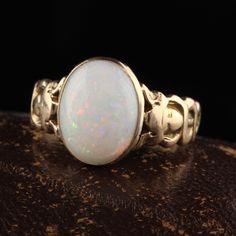 Beautiful Antique Victorian 15K Yellow Gold Opal Asclepios Carved Ring. This gorgeous opal Victorian ring is crafted in 15K yellow gold. The center is a beautiful white opal cabochon with beautiful play of color that is set in a Victorian mounting that has what looks to be a Asclepios figure on each side but is worn. Asclepios was a hero and God of medicine in Greek Mythology. Item #R1295 Metal: 15K Yellow Gold Weight: 6.9 Grams Size: 9 Opal: Approximately 5 ct Measurements: Top of the ring meas Victorian Yellow Gold Opal Wedding Ring, Victorian Style Hallmarked Opal Ring In Yellow Gold, Luxury Gold Victorian Opal Ring, Victorian Yellow Gold Opal Jewelry, Antique 14k Gold Opal Ring, Oval Cabochon, Vintage Opal Engagement Ring, Opal Solitaire Ring, Black Opal Ring, Carved Ring