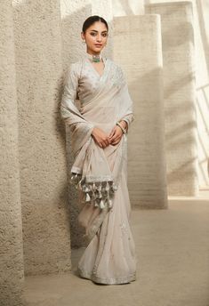 Embodying modern elegance, our ivory dream sari is a masterpiece adorned with breathtaking tarnished silver gota patti and zari work. The contemporary blouse features a deep v-neckline, while the m... Luxury Bohemian Saree-style Blouse, Luxury Elegant Blouse For Reception, Luxury Nida Saree Dress, Luxury Bohemian Saree For Navratri, Luxury Bohemian Saree For Party, Luxury Bohemian Saree For Wedding, Luxury Bohemian Unstitched Saree, Luxury Silver Blouse For Wedding, Necklace For V Neck Blouse