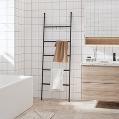 a bathroom with white tiled walls and flooring next to a bathtub, sink, and towel rack