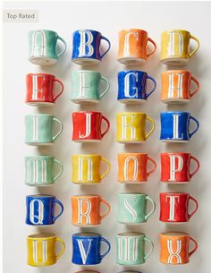 colorful coffee mugs are arranged in the shape of letters on a white wall,