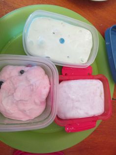 three plastic containers filled with food sitting on top of a green plate next to another container