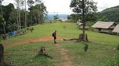 a man standing in the middle of a lush green field next to some houses and trees